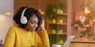 Finance student immersed in study with headphones on, surrounded by financial charts and graphs