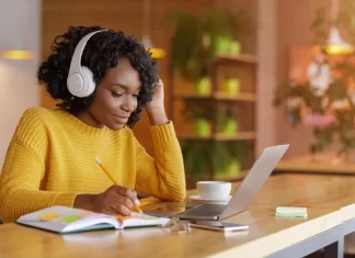 Finance student immersed in study with headphones on, surrounded by financial charts and graphs