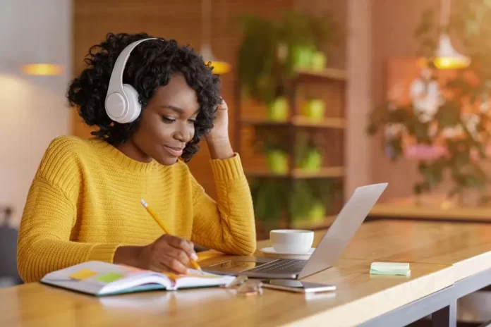 Finance student immersed in study with headphones on, surrounded by financial charts and graphs